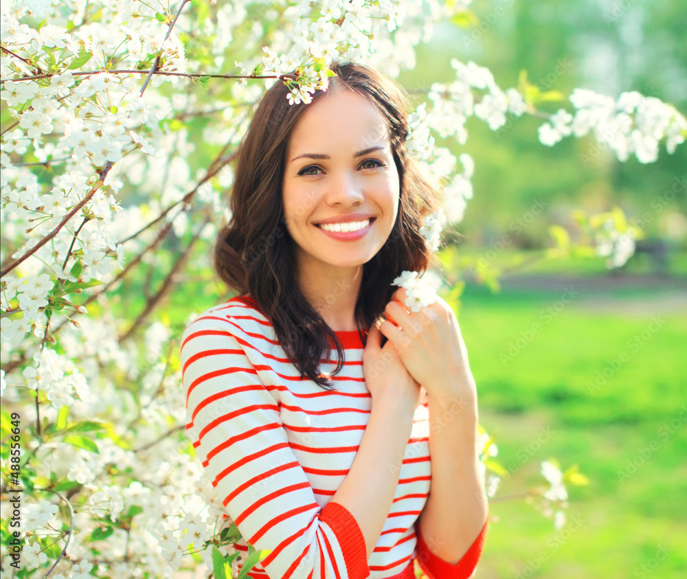 Portrait of beautiful lovely young woman in spring blooming garden on white flowers background