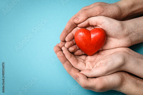 A red heart in the hands of a young guy and a young girl.