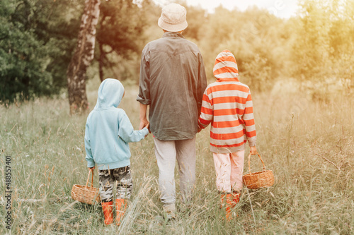 Photography little kids mushroom pickers go to the forest by the hand with their grandmother