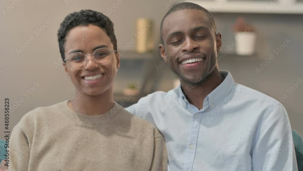 Portrait of Couple Smiling at Camera While Sitting on Sofa Portrait of Couple Smiling at Camera While Sitting on Sofa