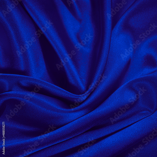 Blue silk satin. Soft wavy folds. Shiny fabric. Luxury background with copy space for design.