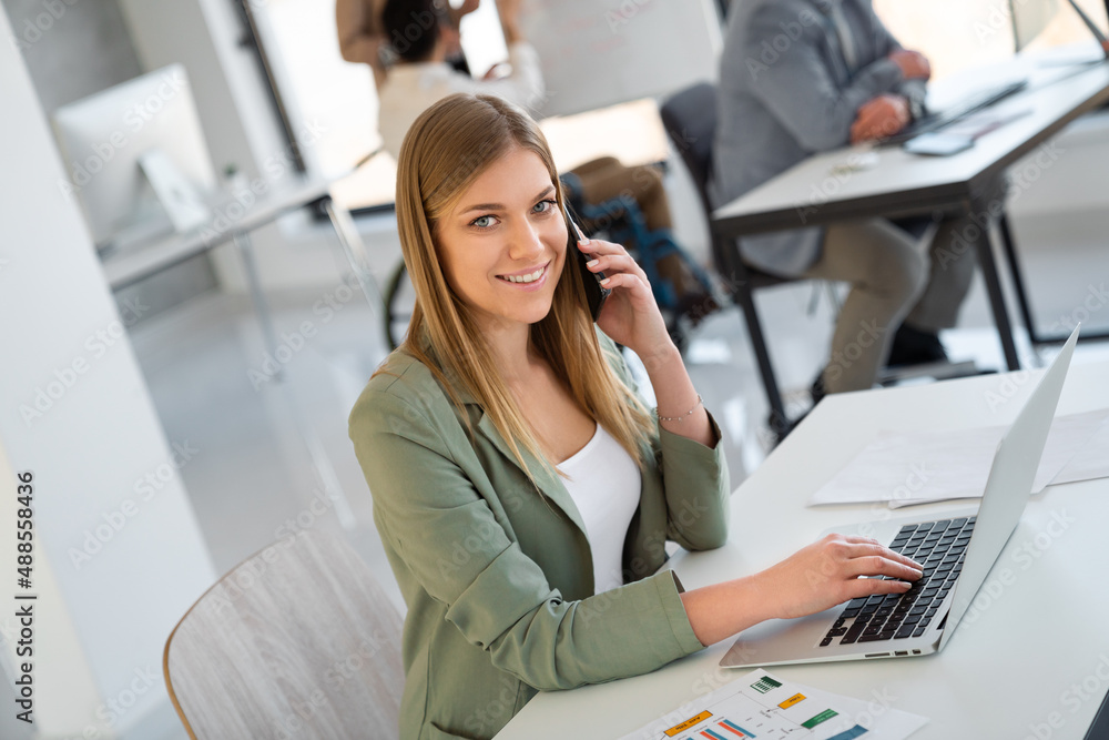 Portrait of young beautiful business woman smiling while working with laptop in office Portrait of young beautiful business woman smiling while working with laptop in office