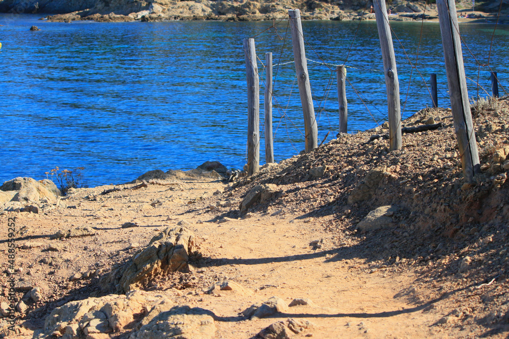 Rocky and sandy footpath with wooden poles along the hiking trail Sentier du Littoral in the beautiful nature reserve at the peninsula Saint Tropez