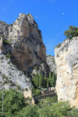 View to the rocks and scarps above the surrounding wall of the village Moustiers-Sainte-Marie near Canyon Gorge du Verdon, Provence, France with its symbol, a golden star at the blue sky 