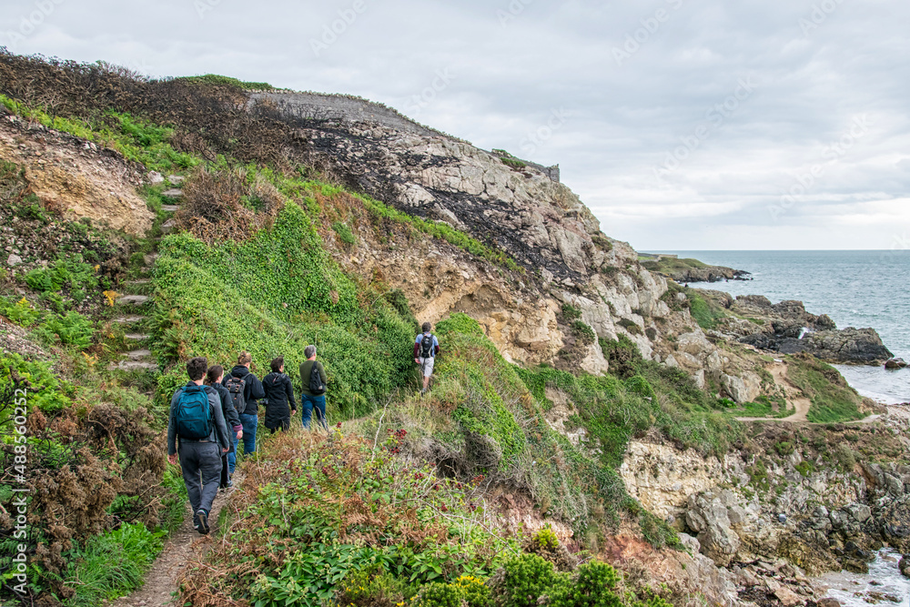 Eine kleine Wandergruppe ist auf einem schmalen Wanderweg an der irischen Küste unterwegs
