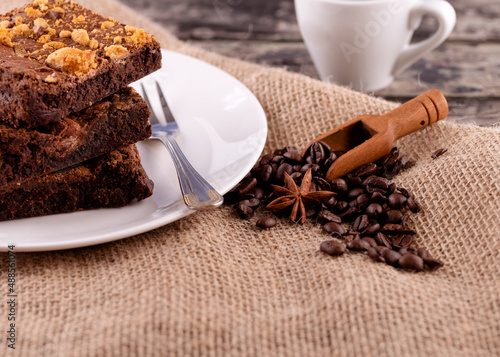 cup of coffee with cake and coffee beans on white plate on wooden table in cafe