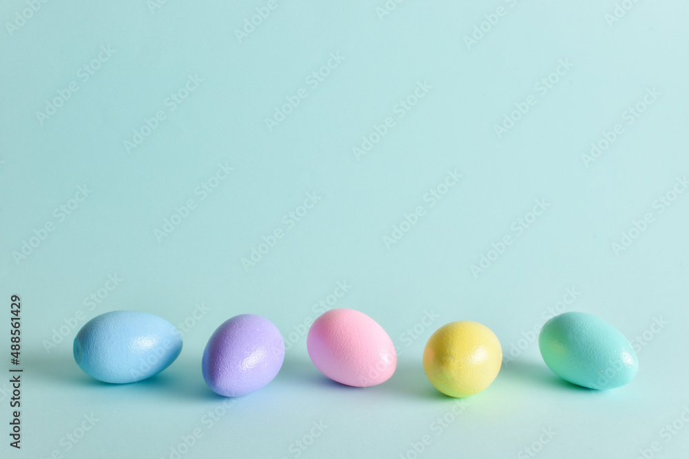 Painted eggs of delicate tones lie on a pale blue background.