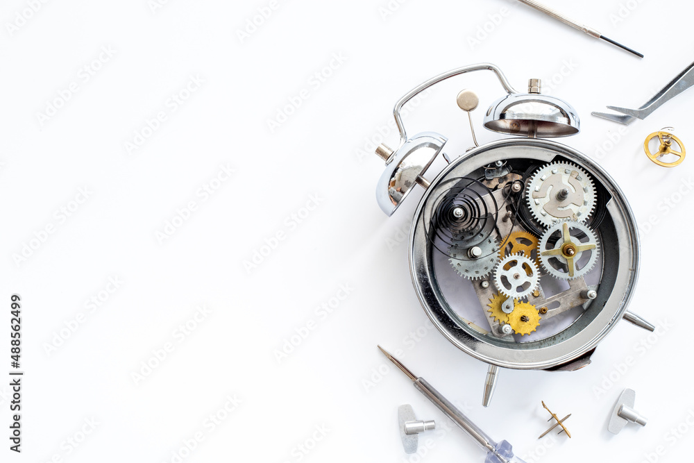 Fototapeta premium Watchmaker tools near watch mechanism of alarm clock