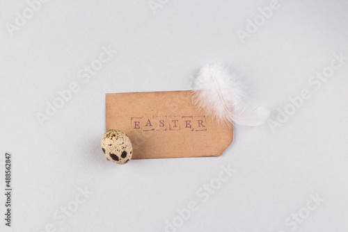 Easter minimal concept. Quail eggs with paper tag as easter symbol. Light grey marble background. Place for your text, copy space.