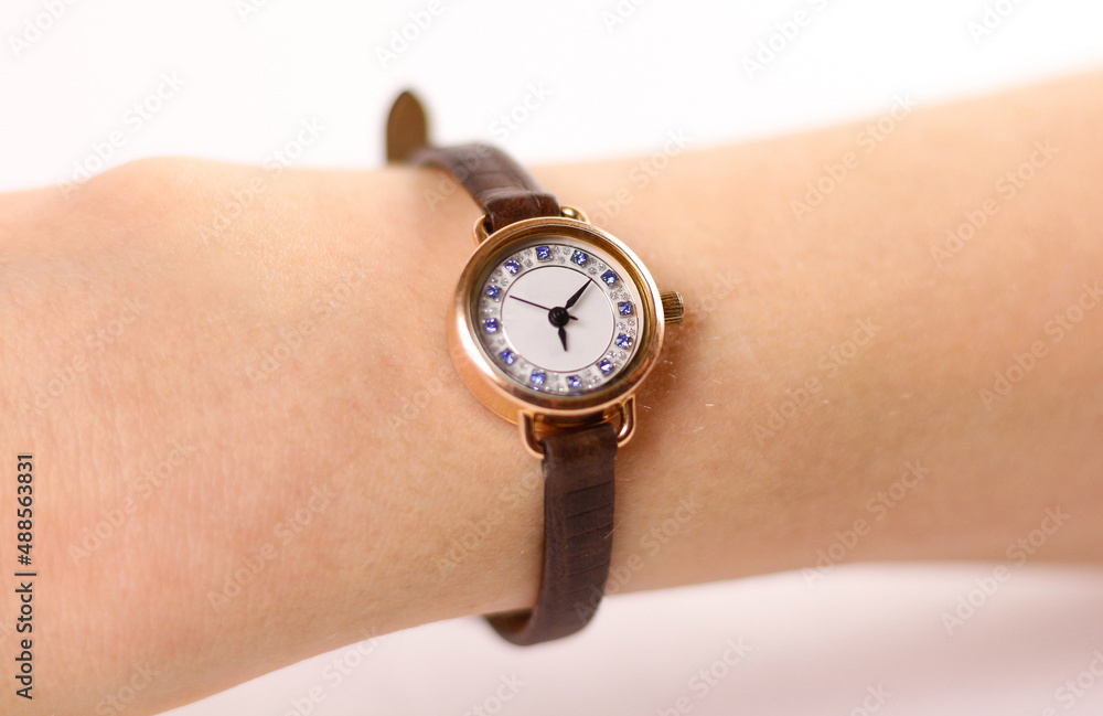 Womens gold watch with leather strap on the hand. On a white background Womens gold watch with leather strap on the hand. On a white background