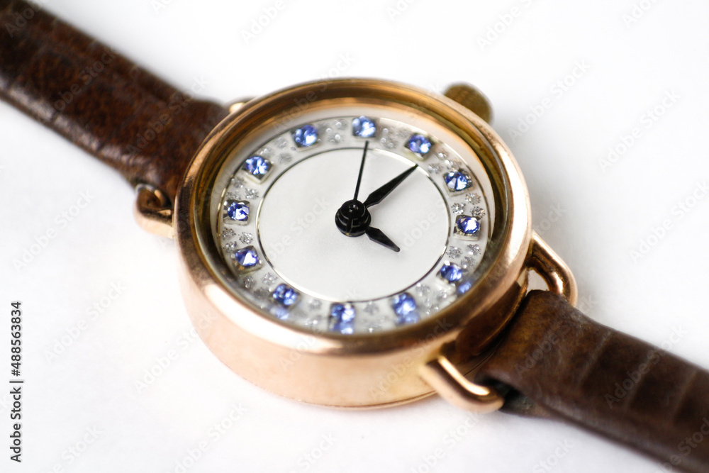 Womens gold watches on a leather strap. Close-up shot. On a white background Womens gold watches on a leather strap. Close-up shot. On a white background