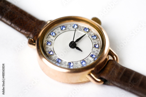 Womens gold watches on a leather strap. Close-up shot. On a white background