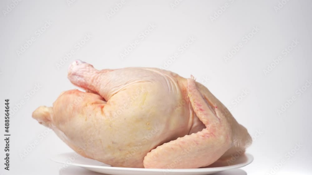 Chilled carcass of homemade chicken rotates on a white background, front view