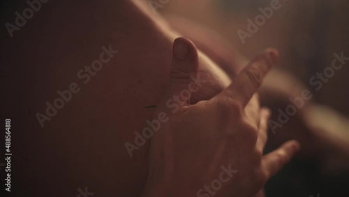 A woman's hand gently strokes a man's shoulder in the sauna. Close-up. Tibetan therapy.