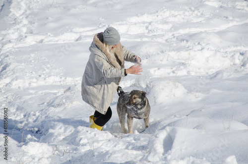 a woman plays with a dog in winter
