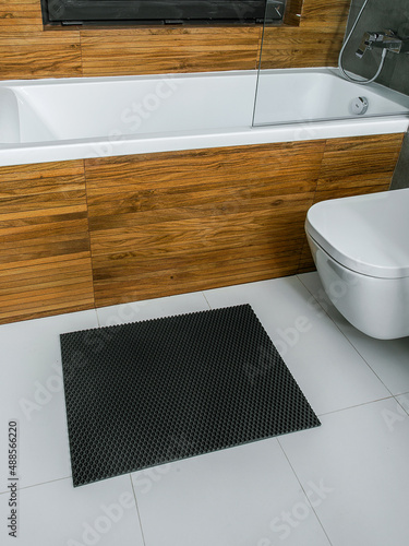A rubber mat on the floor next to the bathtub in the bathroom. Interior design, modern bath