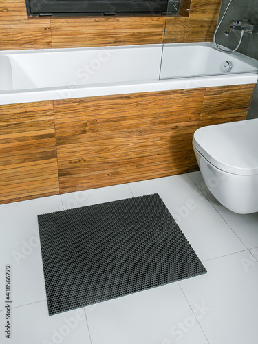 A rubber mat on the floor next to the bathtub in the bathroom. Interior design, modern bath