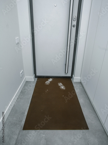 rubber door mat, front door, home with traces of dirt and snow
