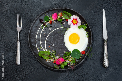 Fried egg with a decor of microgreens, food flowers, sorrel and nasturtium photo