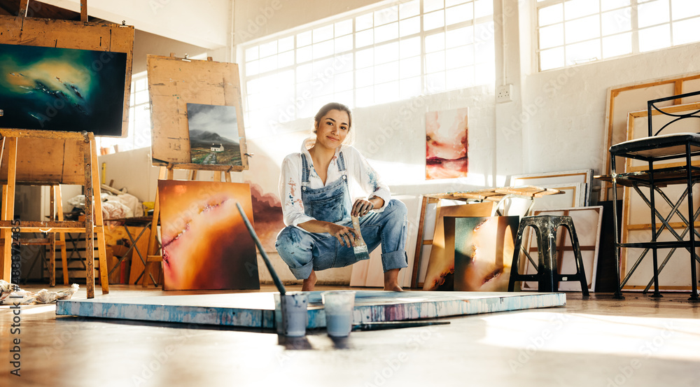 Creative painter squatting close to her painting - obrazy, fototapety, plakaty 
