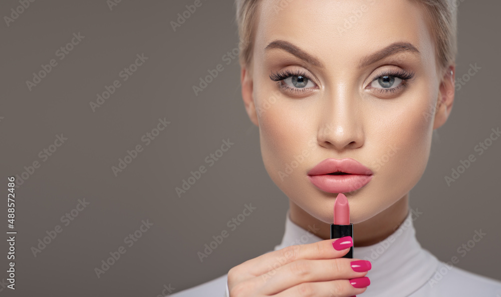 Close-up portrait of a girl. Holds lipstick near her lips. Close-up portrait of a girl. Holds lipstick near her lips.