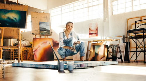 Creative painter squatting close to her painting photo
