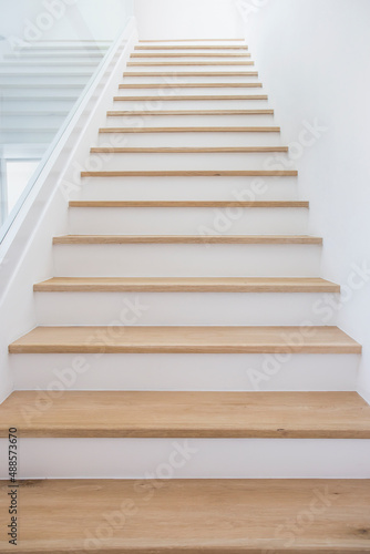 Wooden stairs with clean white walls. © prasong.