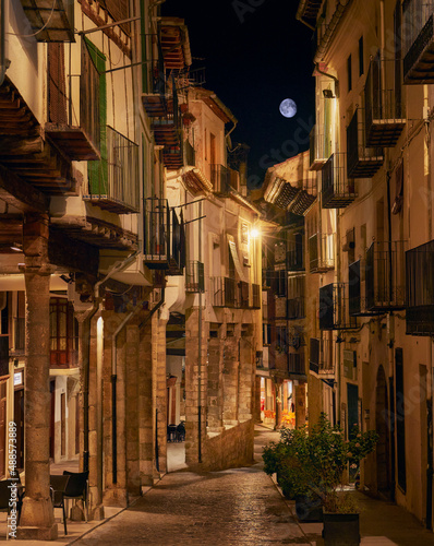 Full moon in medieval porticoed street in Morella  golden light