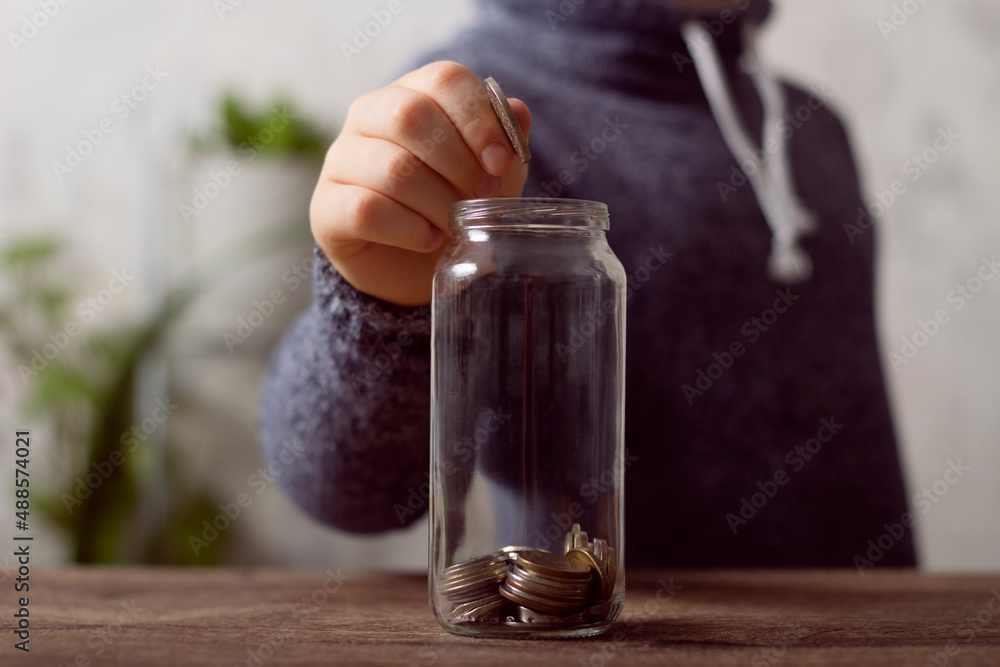 The boy throws a coin into a piggy bank, saves money for a dream. Business-related photography The boy throws a coin into a piggy bank, saves money for a dream. Business-related photography