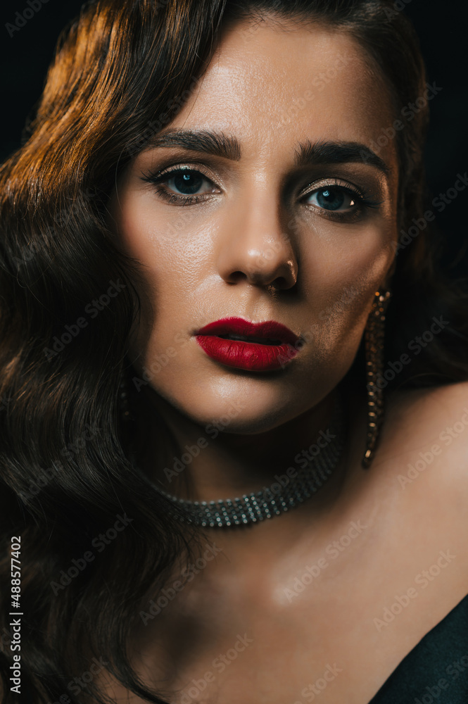 Fototapeta premium Portrait of young woman in Hollywood retro noir style. A beautiful brunette girl with a hairstyle and makeup with jewelry in classic vintage look