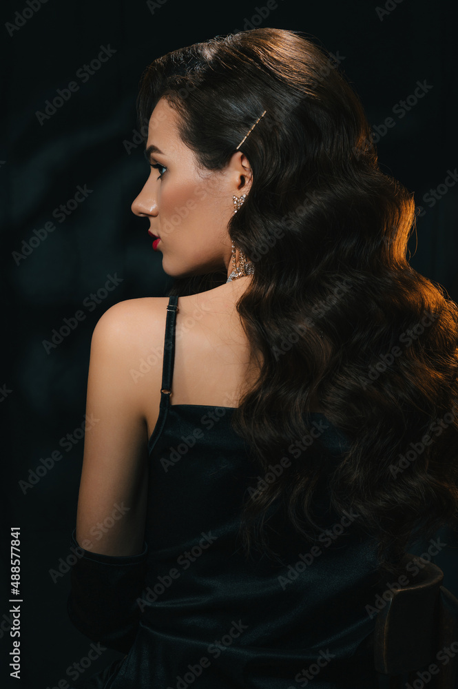stylish woman in classic retro style of 1950s Hollywood movies with a  beautiful hairstyle and makeup. Portrait of girl in vintage look with  jewelry on dark background Stock Photo | Adobe Stock