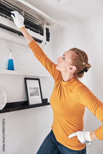 Woman cleaning aircon filters indoor unit at home.