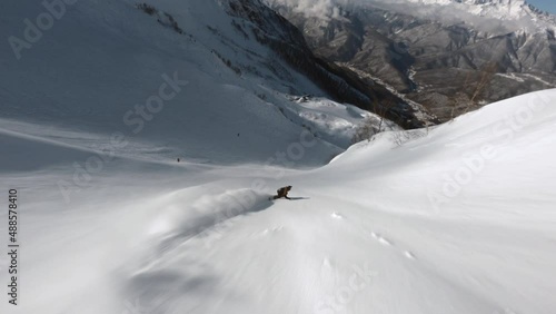 Aerial view sports FPV drone extreme snowboarder freeride on snowboard jumping drop and make tricks on fresh snow. Active sportsman freedom extreme hobby activity winter snowy ski resort mountain