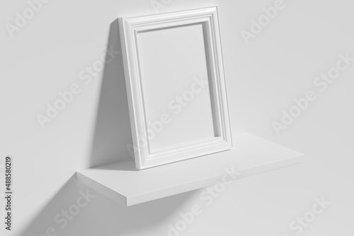 Rectangular photo frame on white shelf leaning at wall top diagonal view
