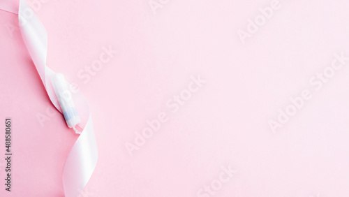 Tampon woman feminine hygiene. Pink ribbon with menstrual tampon on pink background. Menstruation feminine period. Soft tender protection for women critical days.