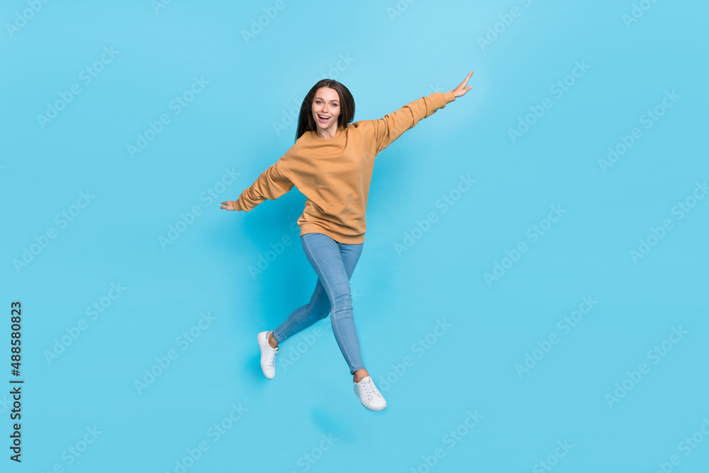 Full body photo of cute millennial brunette lady run wear sweater jeans footwear isolated on blue background