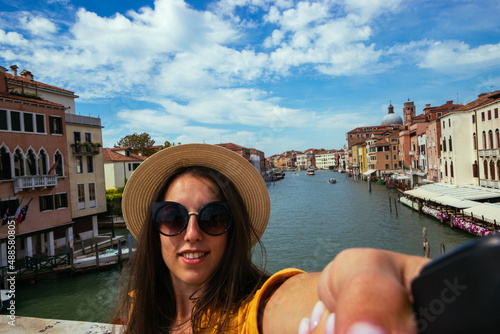 Travel influencers Venice island. Paint building house in Europe Venezia city. Photographer blogger girl with smartphone in Venice San Marco square. Traveling and freelancing, modern lifestyle.