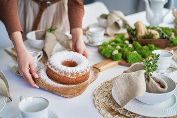 Hands of unrecognizable woman setting table with an easter cake