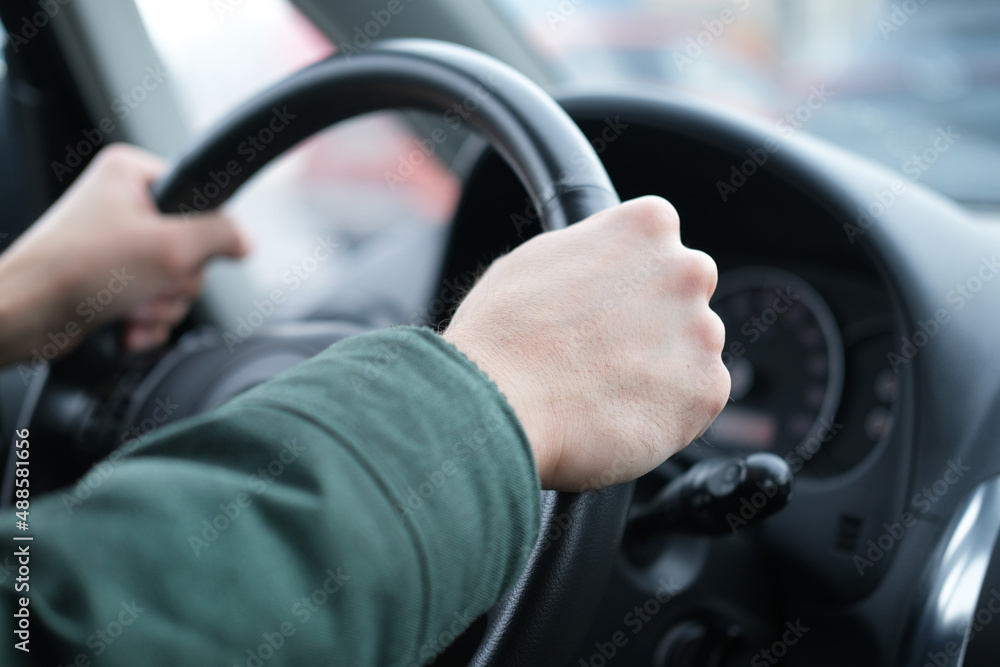 Male hands on the steering wheel of a car close-up