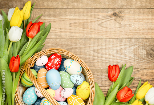 Canvas Print wicker basket with easter eggs and spring tulips on a wooden table top view