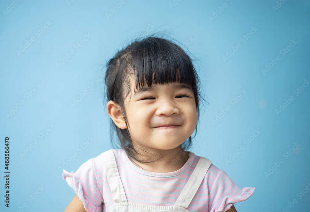 A headshot portrait of a cheerful baby Asian woman, a cute toddler little girl with adorable bangs hair, a child wearing a purple sweater smiling and don't looking to the camera.