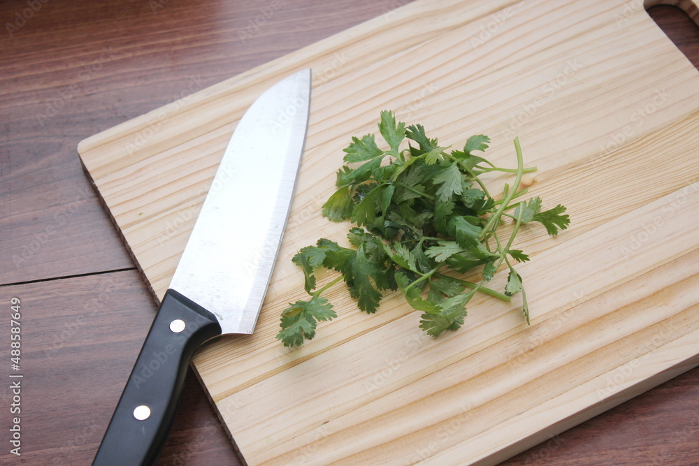 chopped cilantro and knife Place it on a wooden cutting board inside a wooden table. chopped cilantro and knife Place it on a wooden cutting board inside a wooden table.