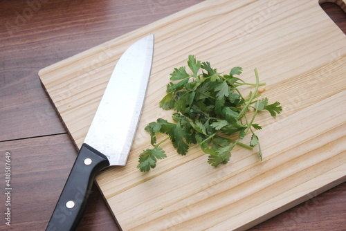 chopped cilantro and knife Place it on a wooden cutting board inside a wooden table.