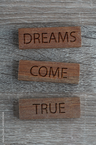 Dreams Come True motivational quotes on a wooden surface