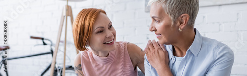positive lesbian women smiling at each other while talking at home, banner