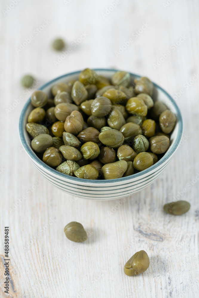 Pickled capers on white wooden surface. Gourmet food. Pickled capers on white wooden surface. Gourmet food.