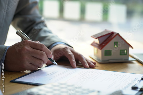 The businessman sign a contract and architectural style of the house.