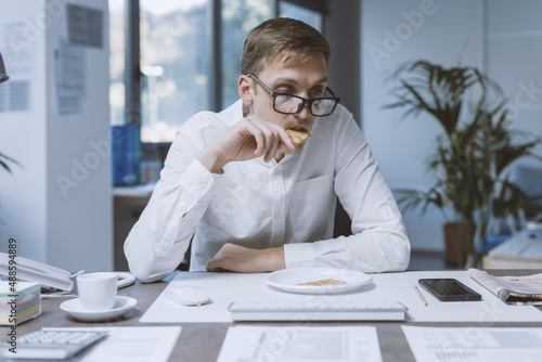 Sad office worker eating a very small meal