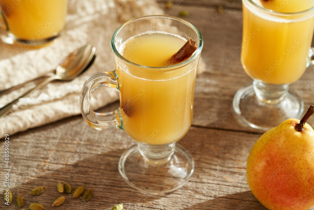 Homemade hot pear beverage with winter spices on a wooden table Homemade hot pear beverage with winter spices on a wooden table