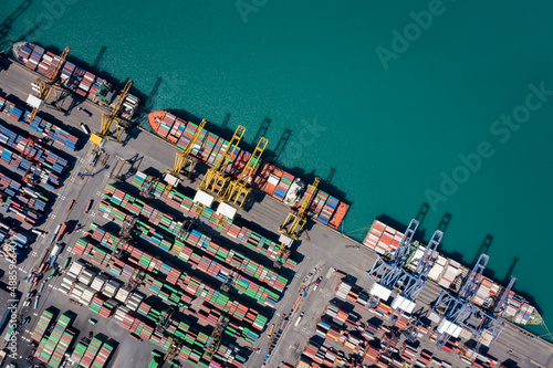 container ship at sea port and working crane bridge loading container for import export, international by shipping or transportation concept photograph from drone